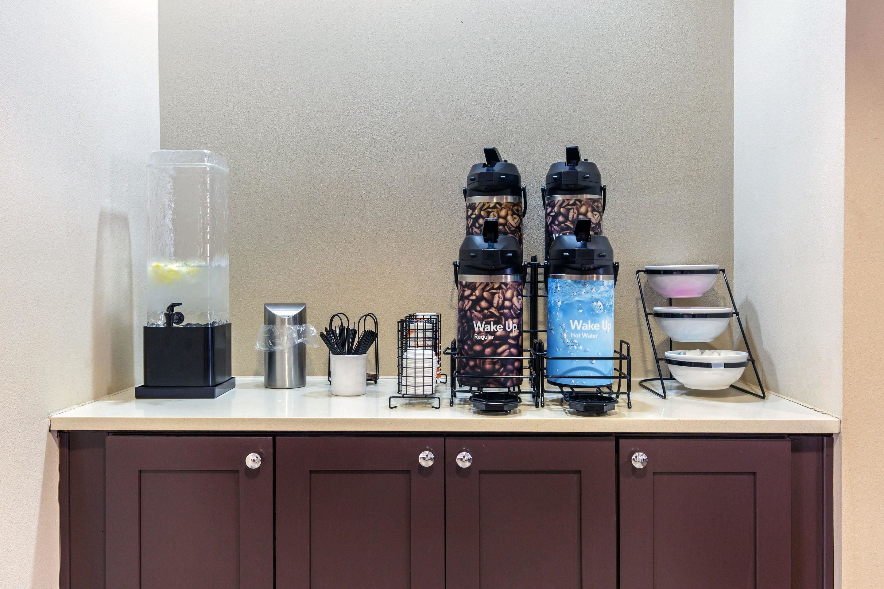Eine Kaffeestation mit zwei Kaffeemaschinen, einem Wasserspender und einer Kaffeemühle auf einer Arbeitsplatte.