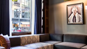 A modern living room with a glass coffee table, leather sofas, and a large window with curtains. - Dossier Hotel (Portland)