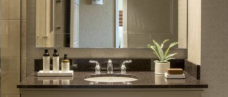 A bathroom with a double sink, a large mirror, and a potted plant.