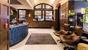 A bar area with a counter, seating, and shelves of bottles. - Dossier Hotel (Portland)