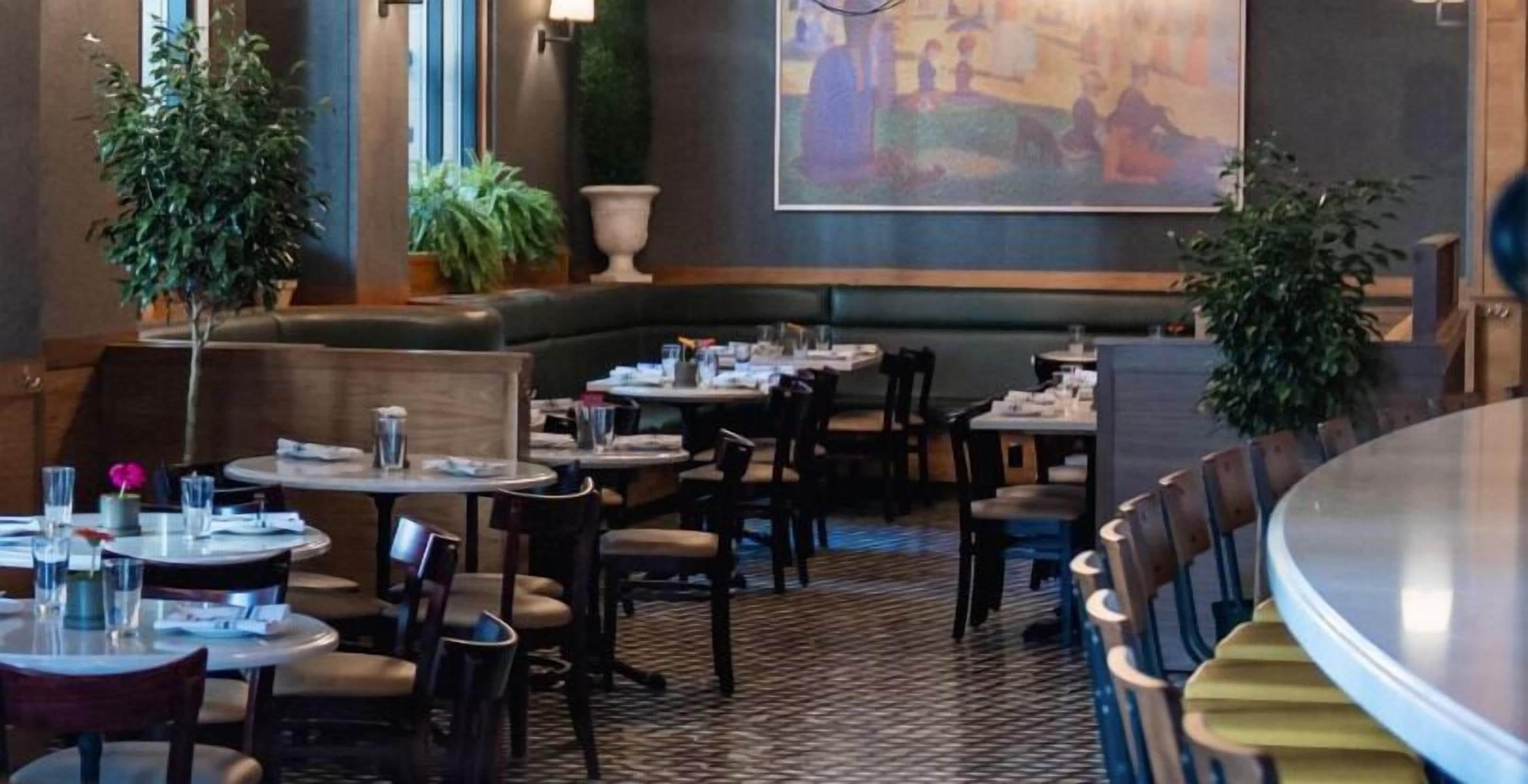 Ein Restaurant mit runden Tischen, Sitzbänken und einem großen Wandgemälde.