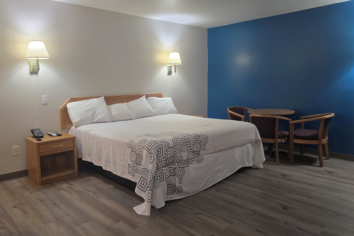 A hotel room with a bed, bedside lamps, a desk, and a chair.