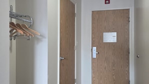 A hallway with a coat rack, two wooden doors, and a metal chair. - Economy Inn (Nephi)