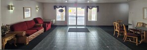 A hotel lobby with a red sofa, a wooden table with chairs, and a tiled floor. - Economy Inn (Nephi)