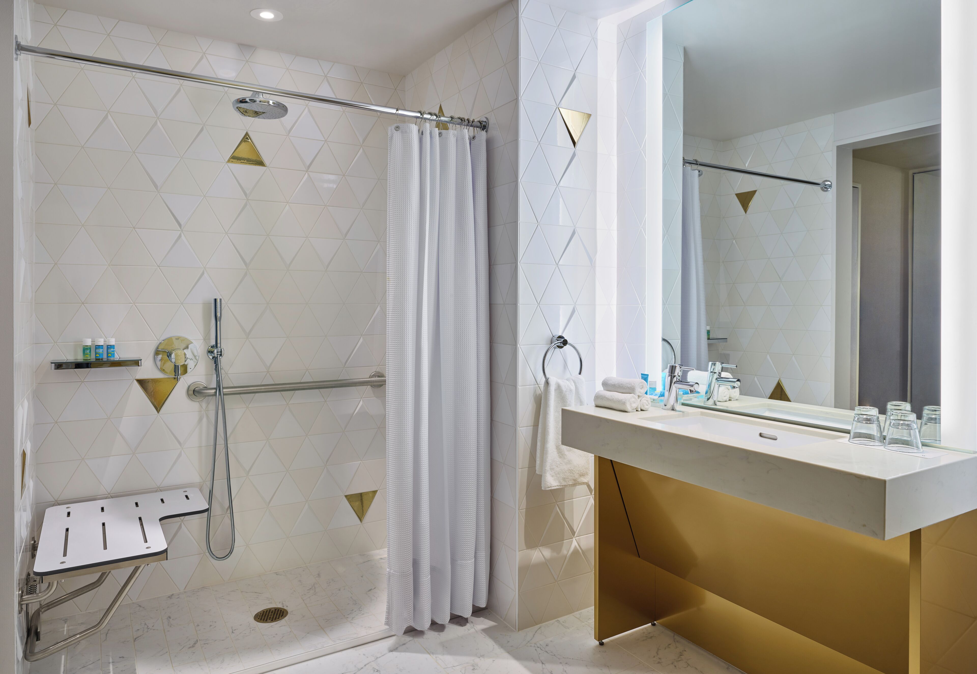 Un baño moderno con ducha, tocador con espejo y perchero para toallas.