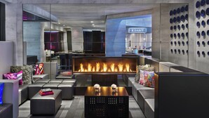 A modern lounge area with a central fire feature, seating arrangements, and a wall with decorative plates. - W San Francisco (San Francisco)