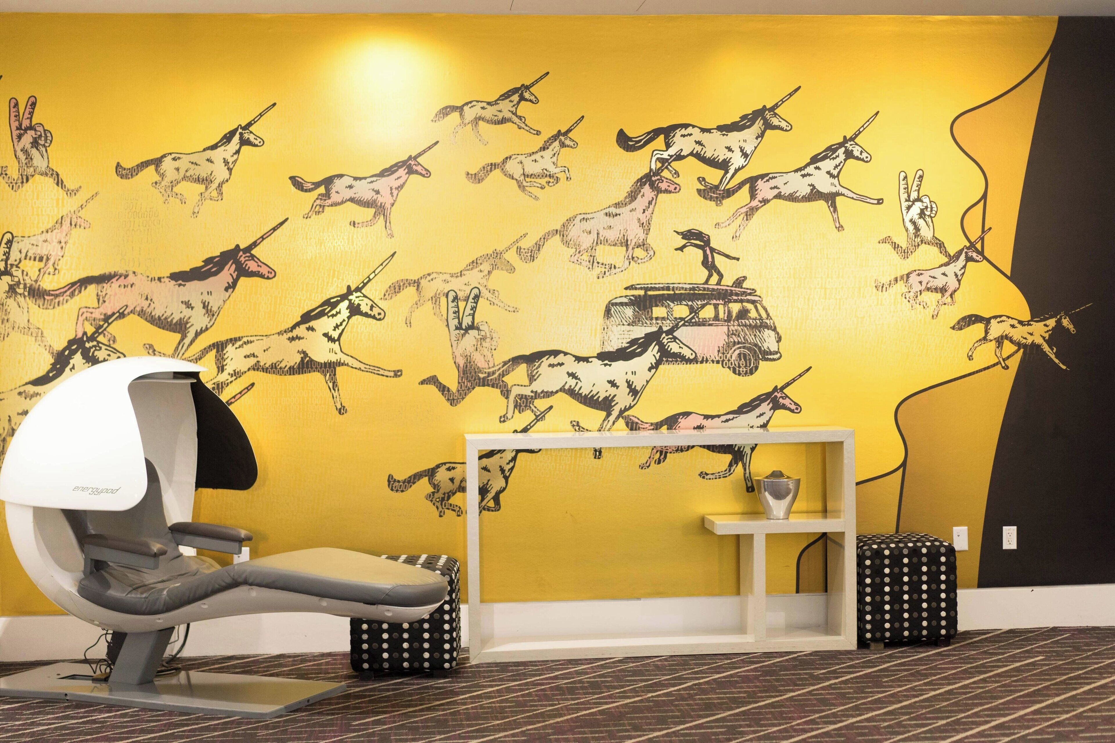 A dental chair in a room with a yellow wall featuring a mural of horses and a car.