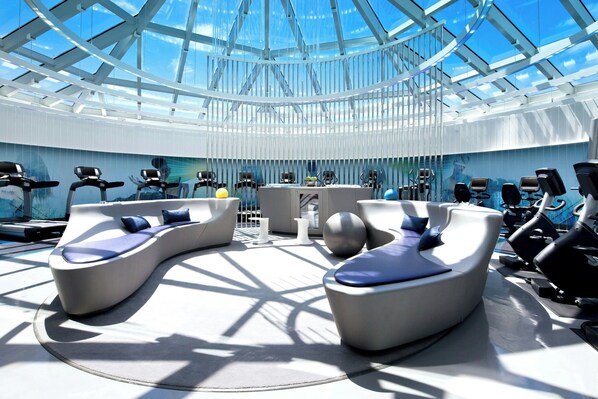 A modern gym with exercise equipment and seating areas.