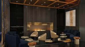 A modern lounge with dark wood paneling, a fireplace, blue sofas, and round coffee tables. - W San Francisco (San Francisco)