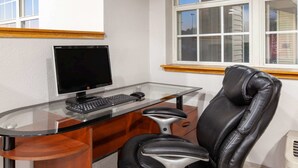 A home office with a glass desk, a black leather chair, a computer monitor, and a keyboard. - Microtel Inn & Suites by Wyndham Pittsburgh Airport (Pittsburgh)