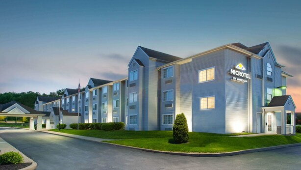 A microhotel with a modern design, featuring multiple floors and a well-lit entrance. - Microtel Inn & Suites by Wyndham Pittsburgh Airport (Pittsburgh)