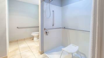 Un baño con ducha, inodoro y un taburete pequeño.