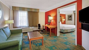 A hotel room with a bed, a desk, a chair, a sofa, and a television.