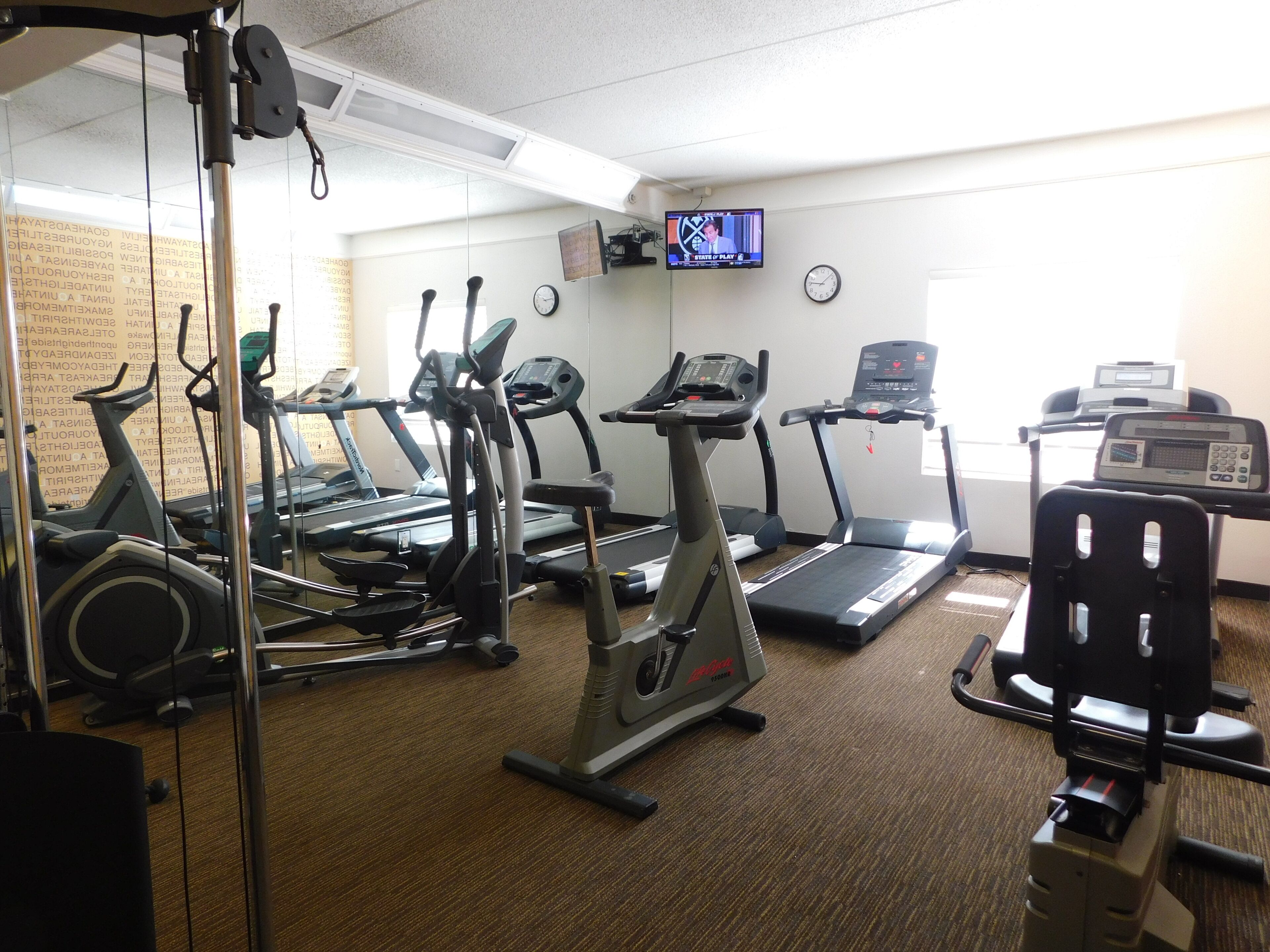 A gym with multiple treadmills, elliptical machines, and a stationary bike.