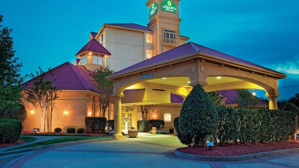 A hotel with a prominent tower, a covered entrance, and well-lit landscaping.