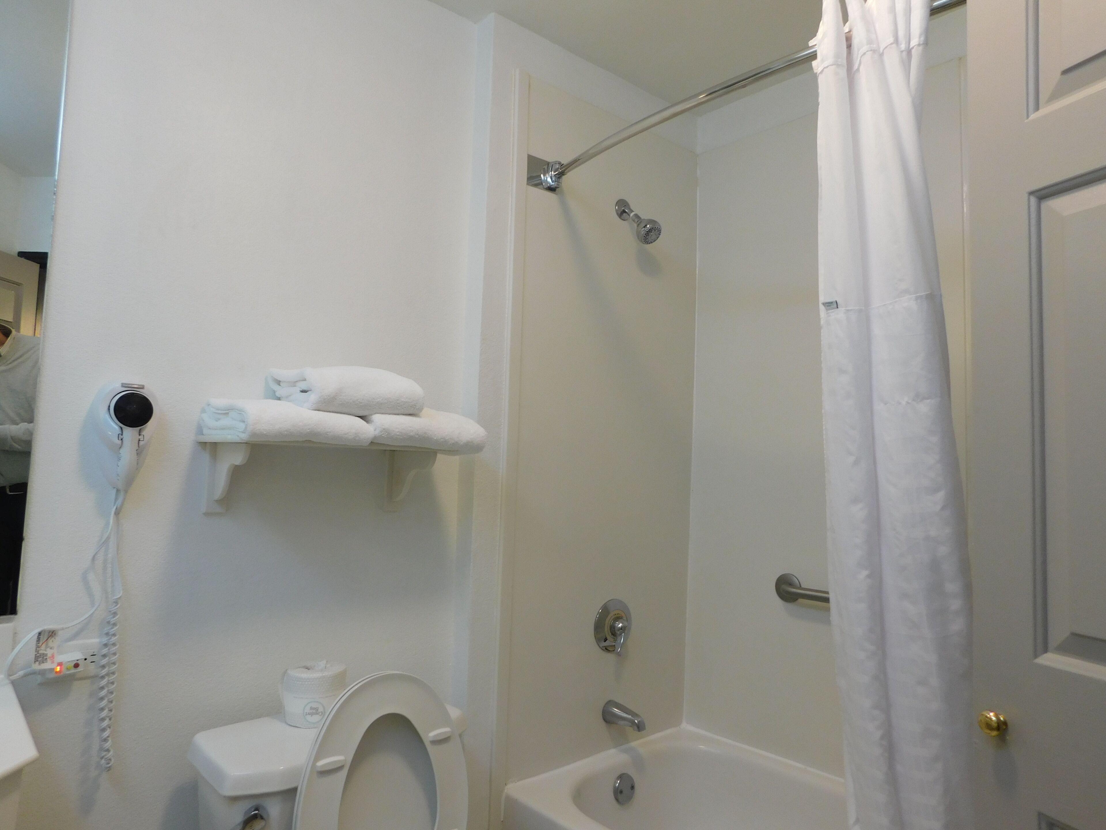 A bathroom with a toilet, a shower with a glass door, and a towel rack with towels.