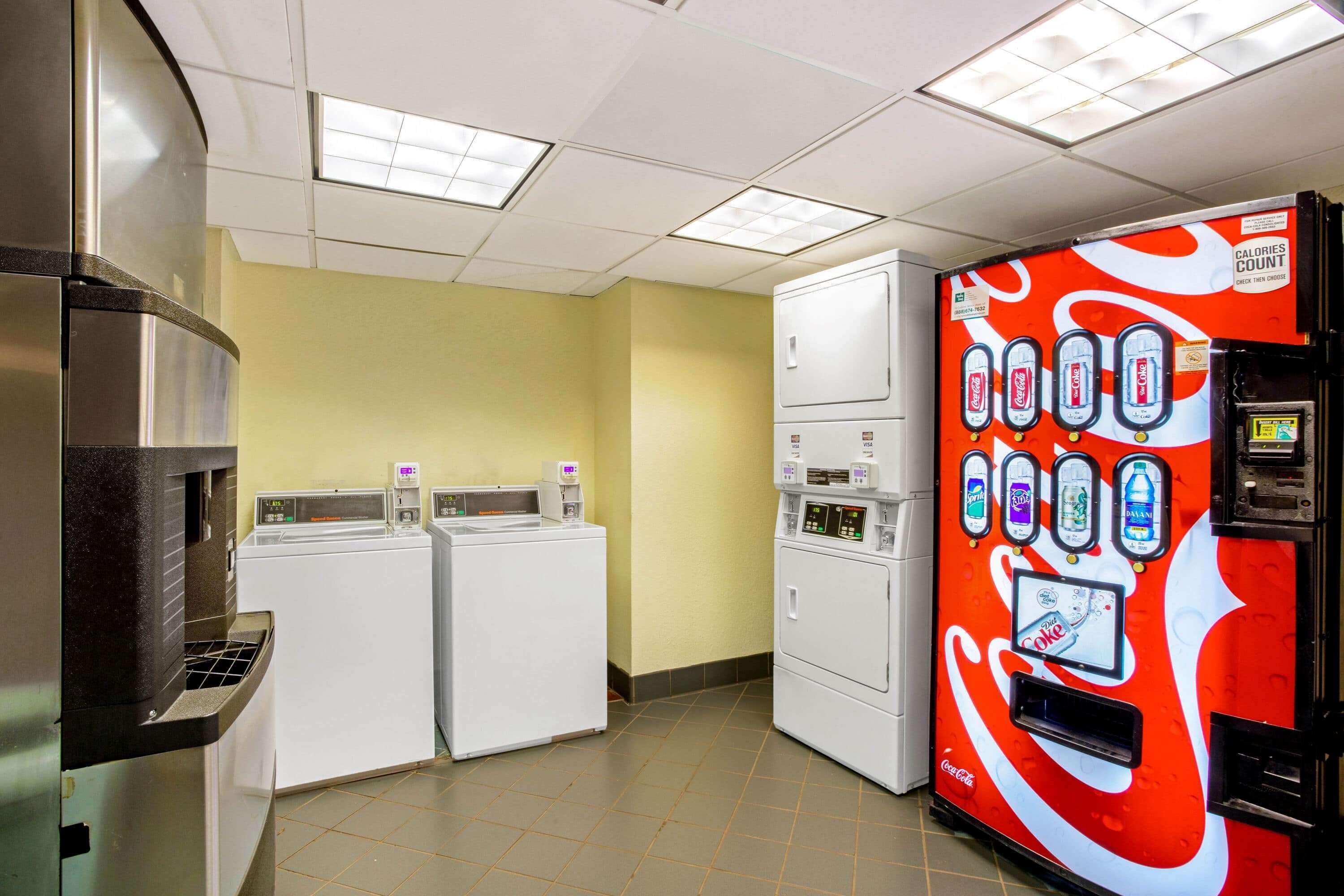 Een ruimte met wasmachines, drogers, een automaat en een magnetron.