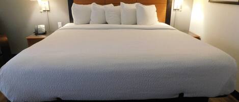A large bed with a wooden headboard, white bedding, and two bedside lamps.