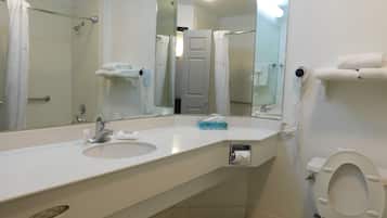 A bathroom with two sinks, a mirror, a toilet, and a shower area.