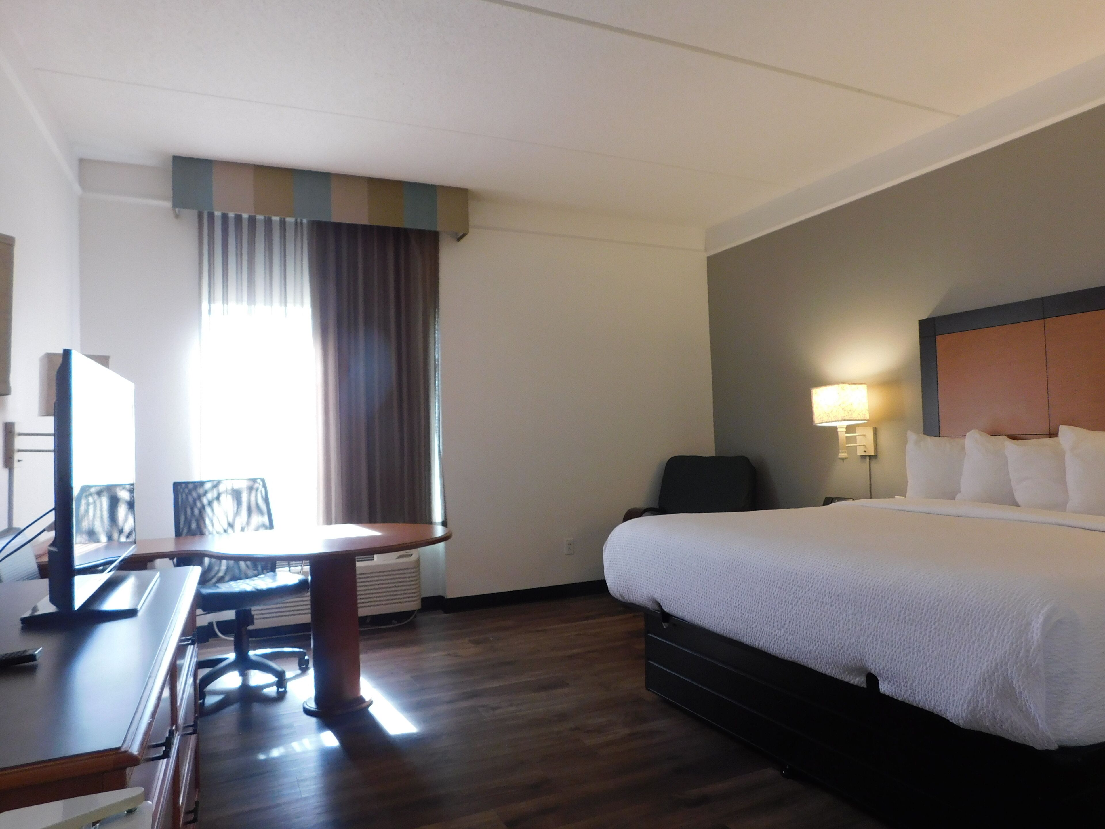 Una habitación de hotel con cama, escritorio, silla y televisor.