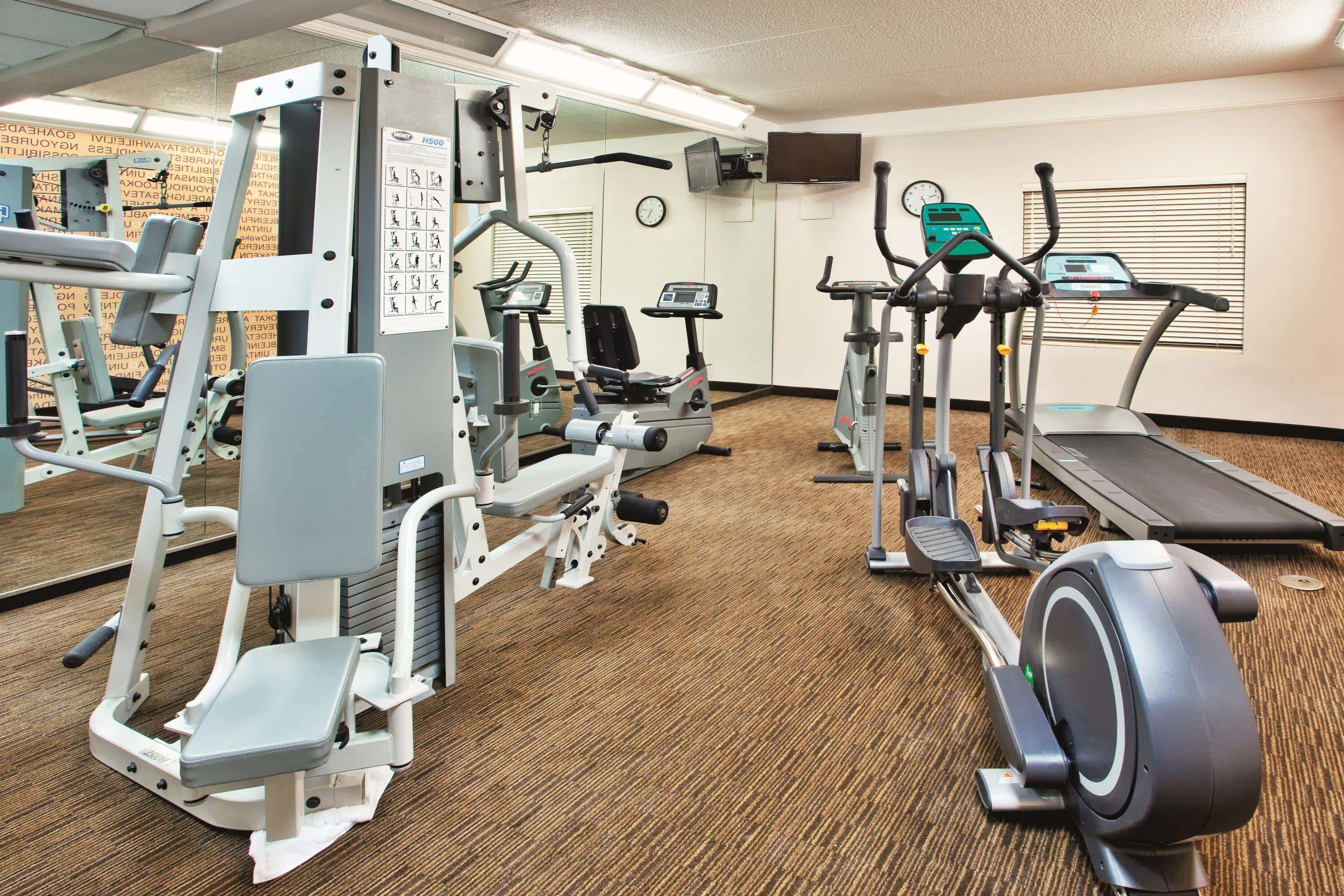A gym with various exercise equipment including treadmills, elliptical machines, and weight machines.