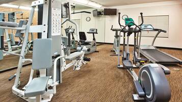 A gym with various exercise equipment including treadmills, elliptical machines, and weight machines.