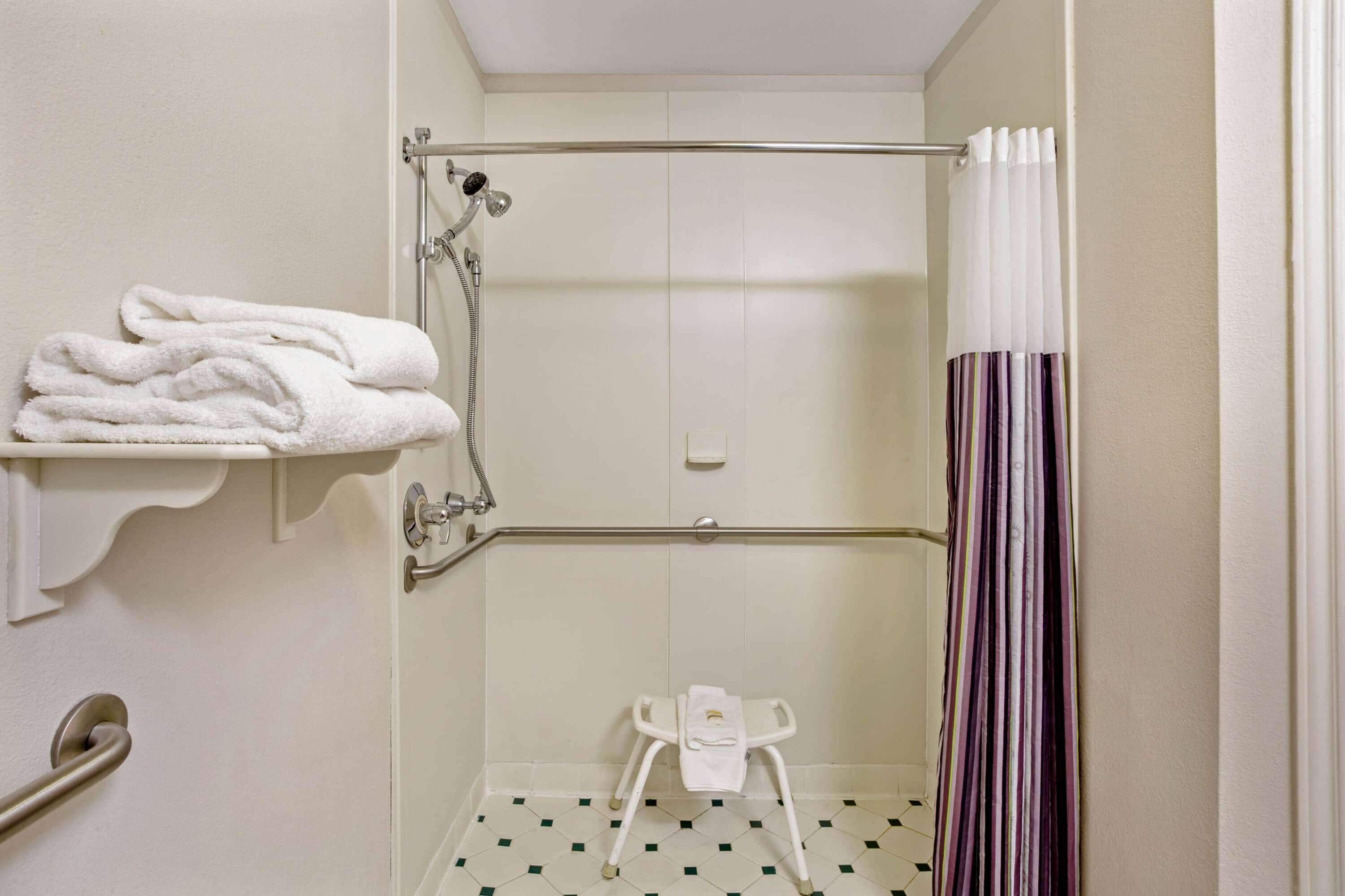 A small, clean bathroom with a shower, a toilet, and a towel rack.
