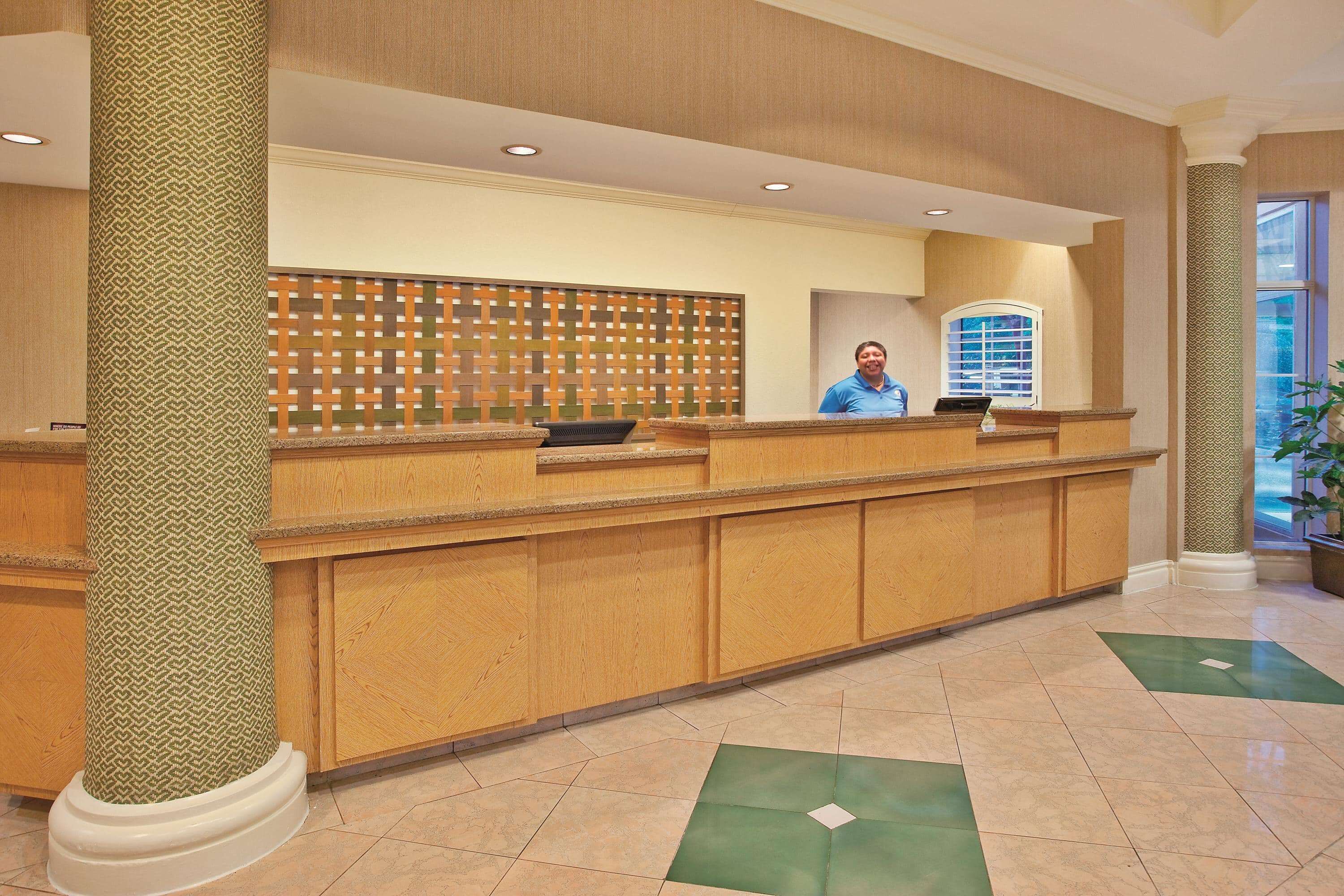 A reception desk with a patterned column, a decorative wall, and a window with blinds.