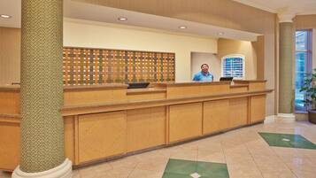 A reception desk with a patterned column, a decorative wall, and a window with blinds.