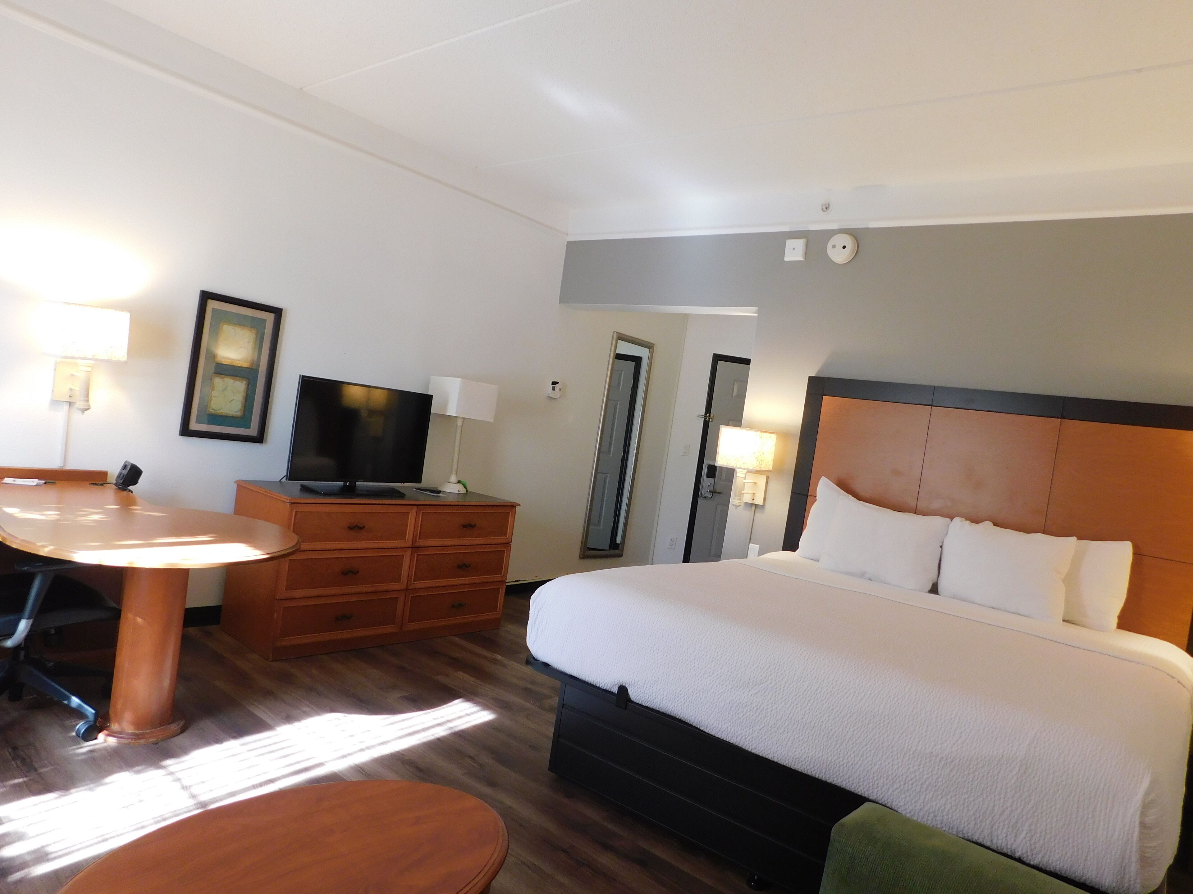 A hotel room with a bed, a desk, a television, and a dresser.