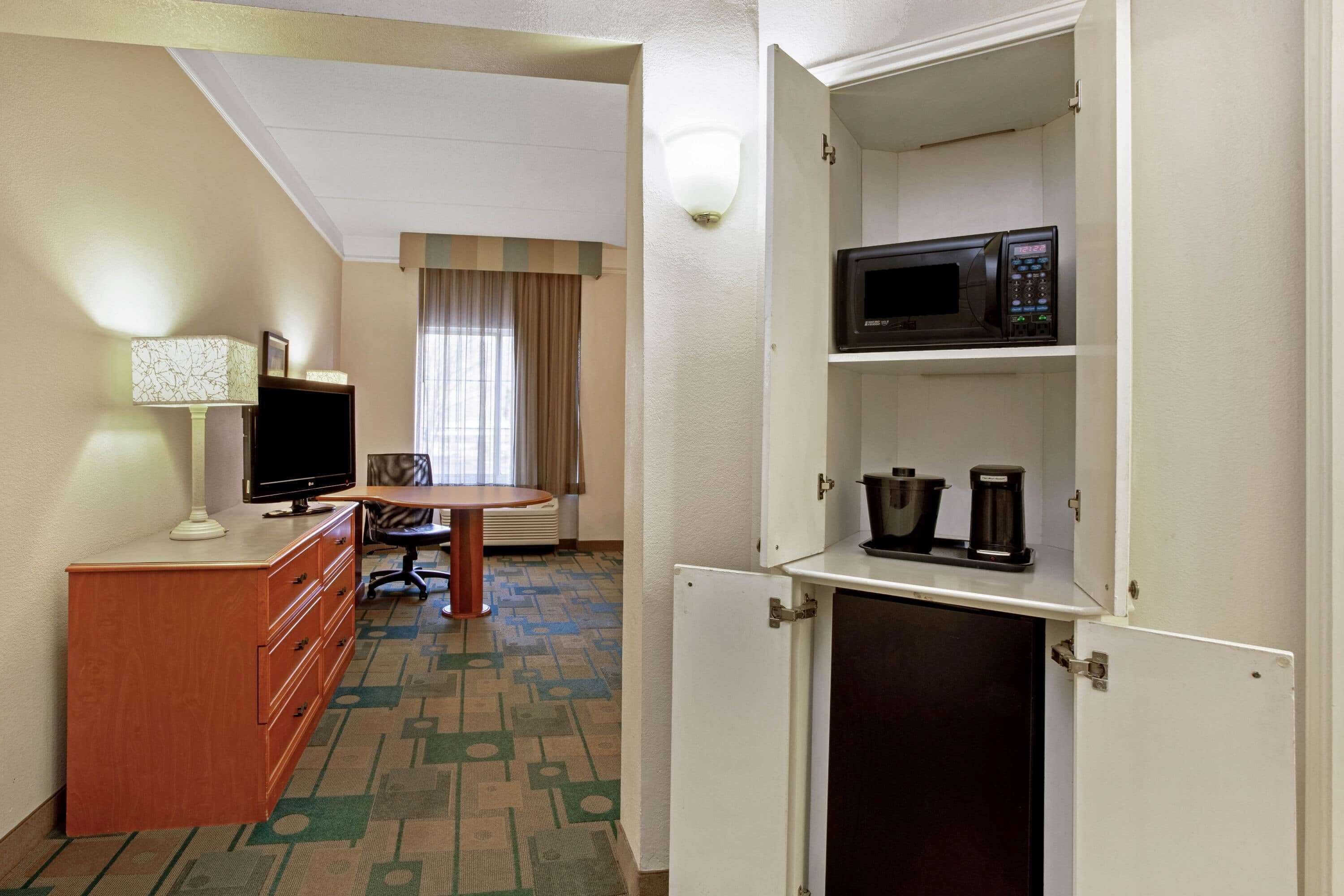 A hotel room with a desk, a television, a microwave, and a coffee maker.