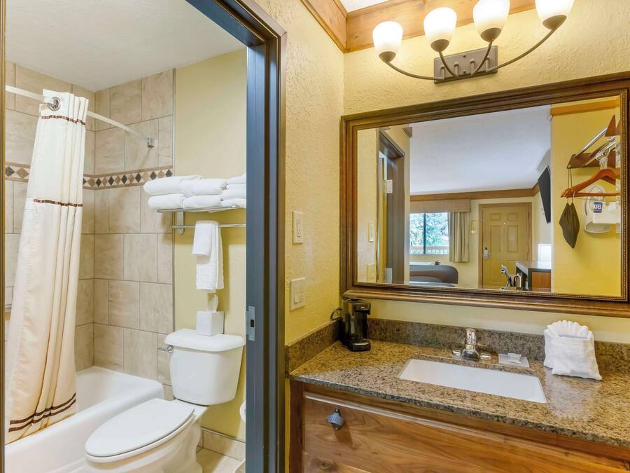 Ein Badezimmer mit Dusche, Toilette, Waschbecken und einem beleuchteten Spiegel.