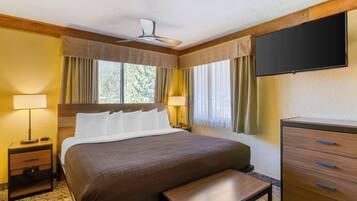 A hotel room with a bed, bedside tables, a TV, and a dresser.