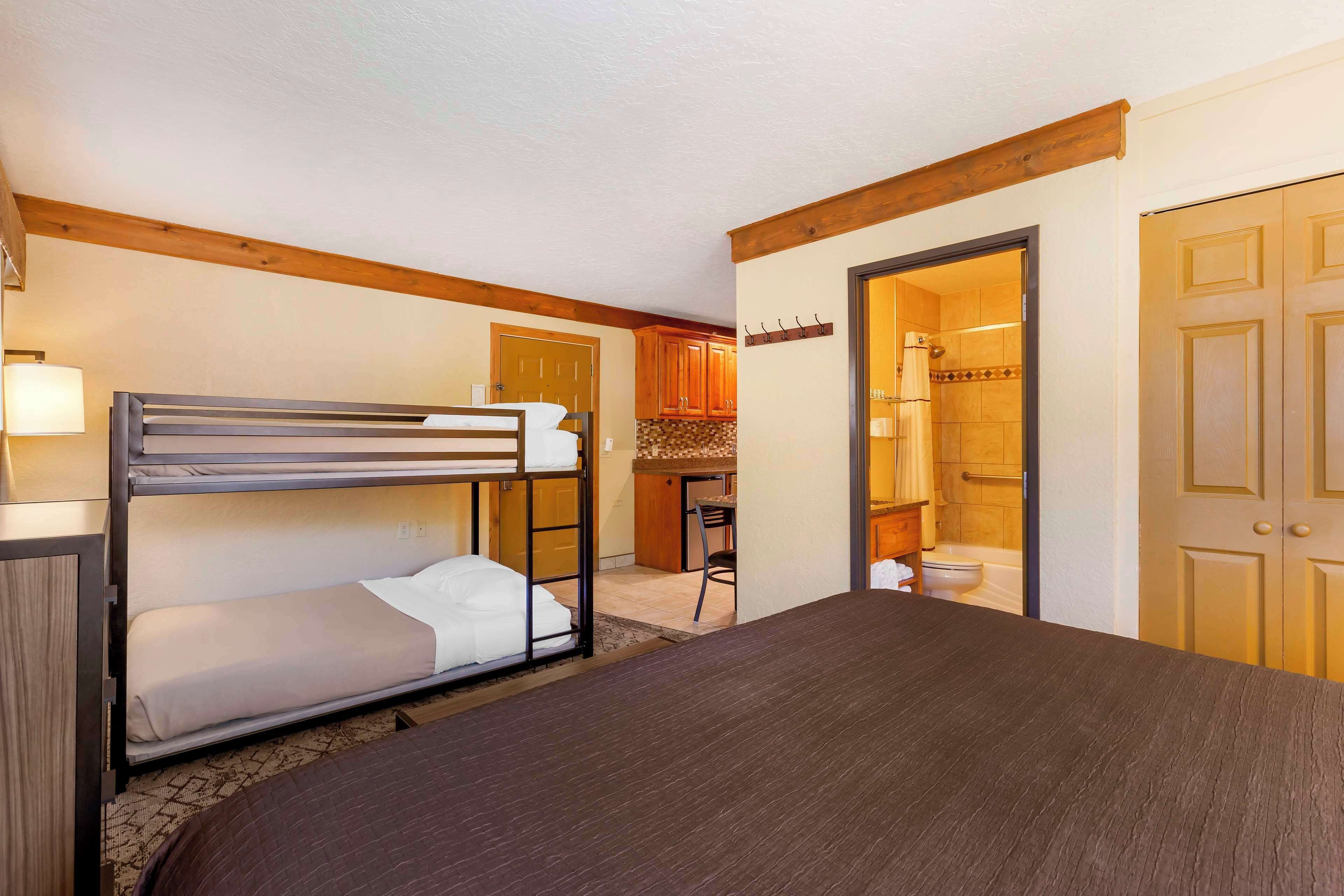 A room with a bunk bed, a desk, and a bathroom visible through an open door.