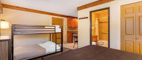 A room with a bunk bed, a desk, and a bathroom visible through an open door.