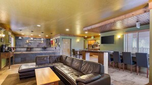 A modern interior with a leather sectional sofa, wooden table, and a bar area with stools. - Best Western Rivers Edge (Red River)