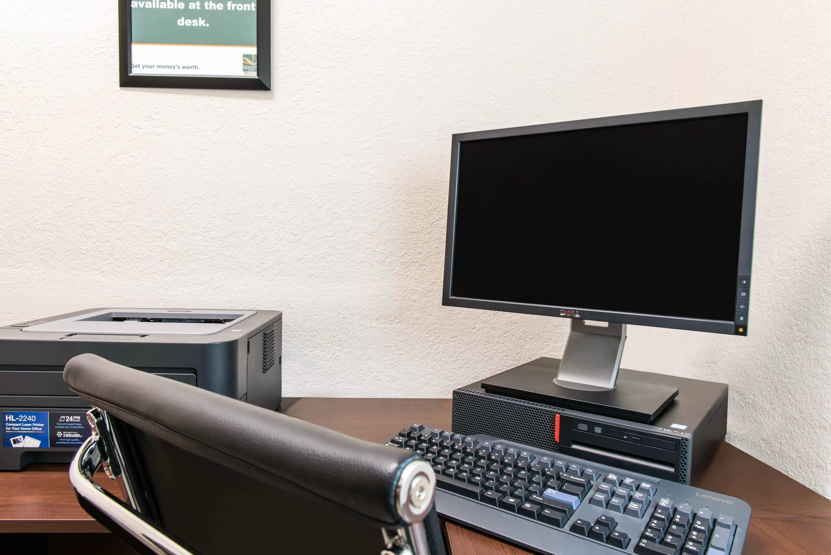 Un escritorio con monitor de computadora, teclado e impresora.