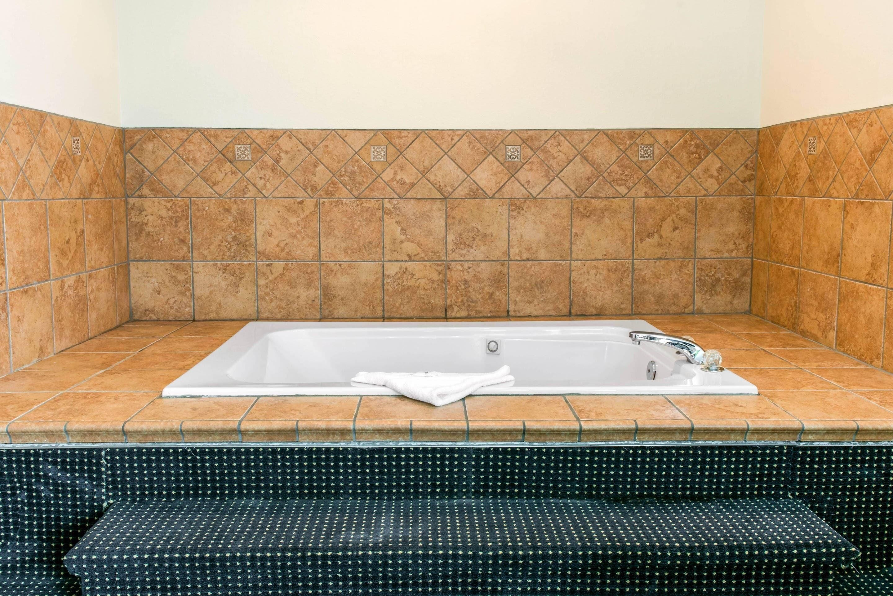 A bathroom with a bathtub, tiled walls, and a patterned bench.