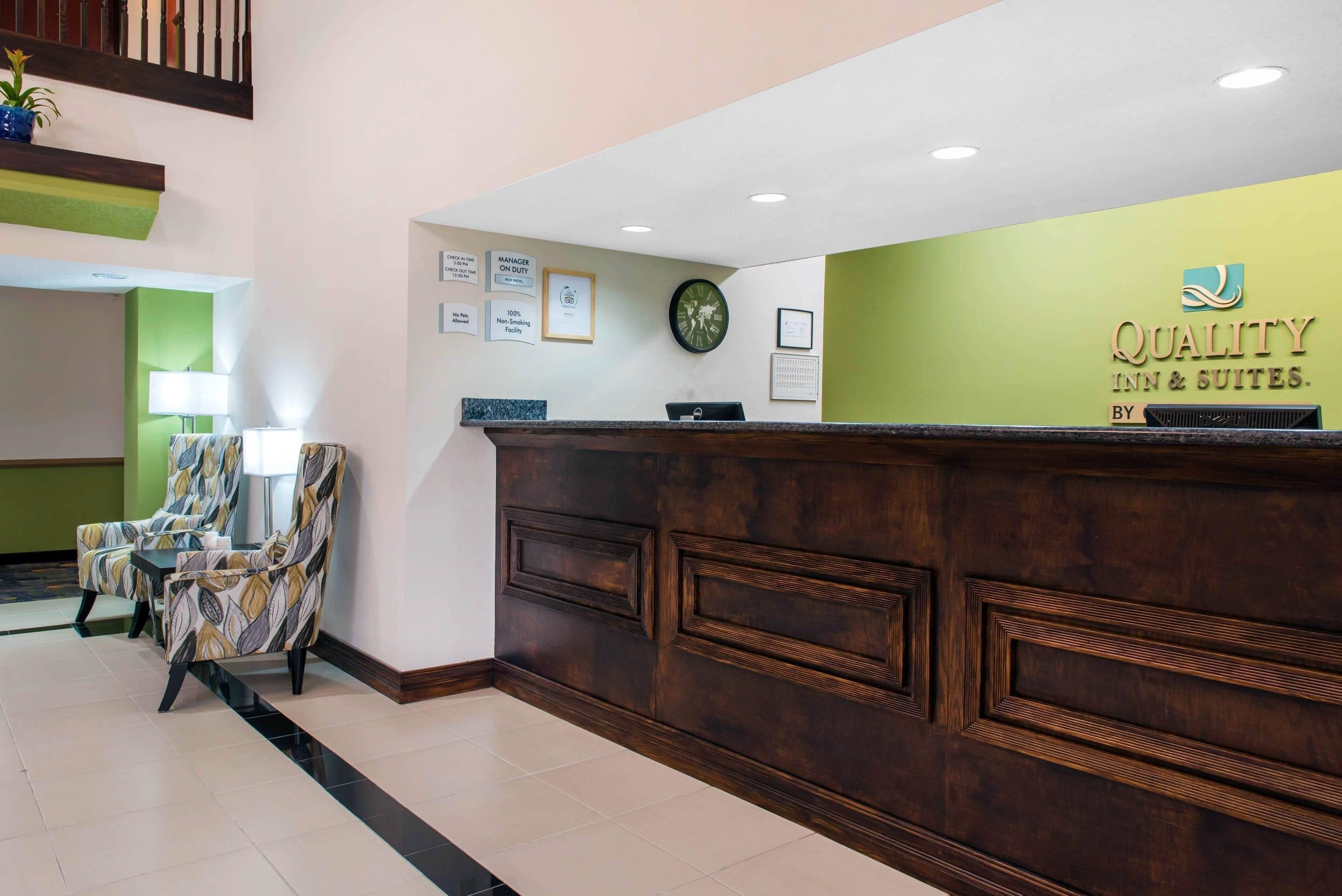 Un mostrador de recepción con una pared verde, diplomas enmarcados y un reloj.