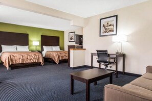 Ein Hotelzimmer mit zwei Betten, einem Schreibtisch, einem Stuhl, einer Lampe und einem Fernseher.