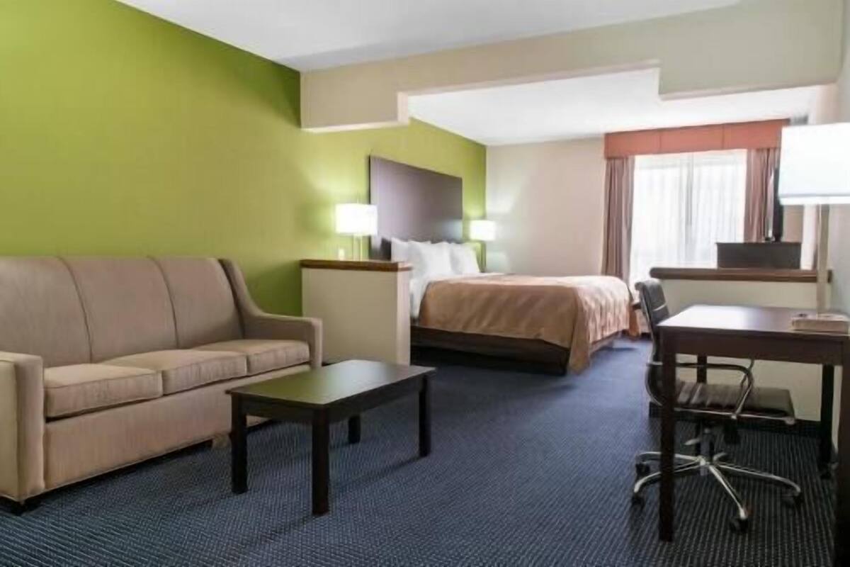 Une chambre d’hôtel avec un lit, un canapé, un bureau et une chaise.