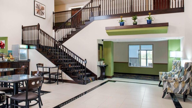 Un hall d’entrée spacieux avec un escalier, un coin repas avec des chaises et une table, et un comptoir d’accueil.