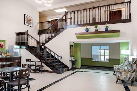 A spacious lobby with a staircase, a dining area with chairs and a table, and a reception desk.. Quality Inn & Suites Anderson I-69