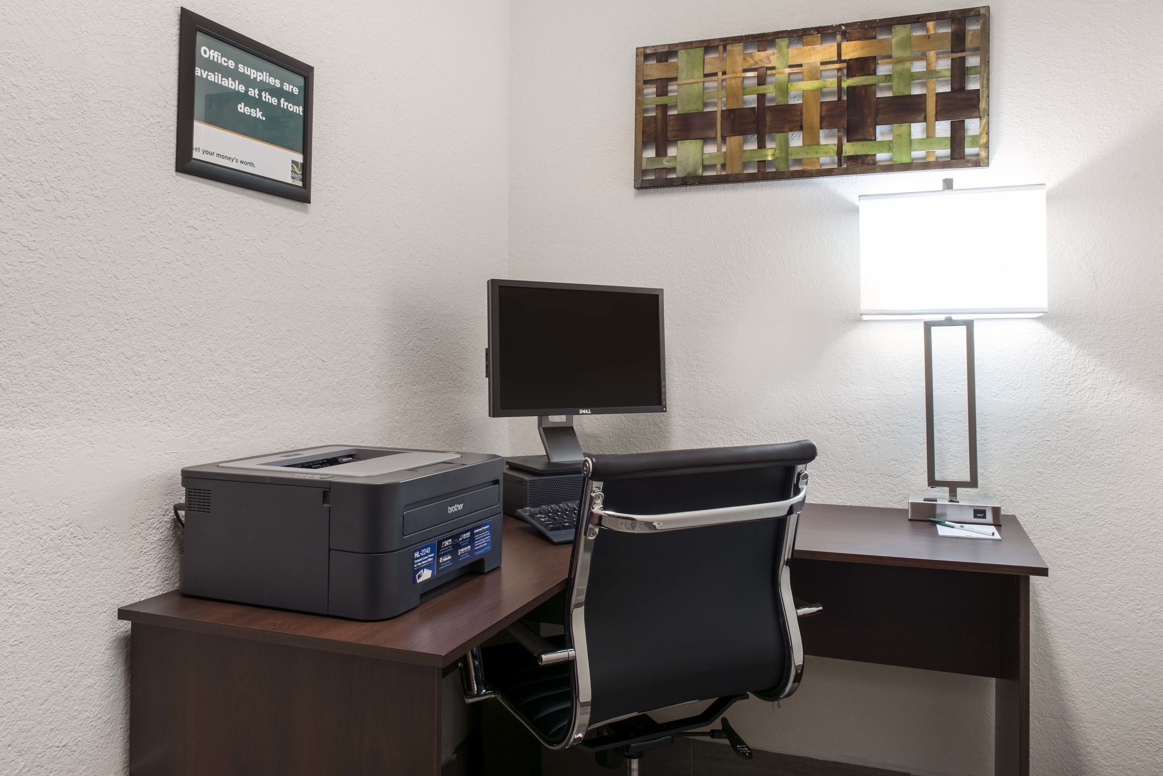 A desk with a printer, a computer monitor, and a chair.