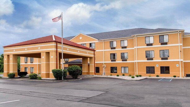 A multi-story hotel with a covered entrance, a flag, and a parking lot.