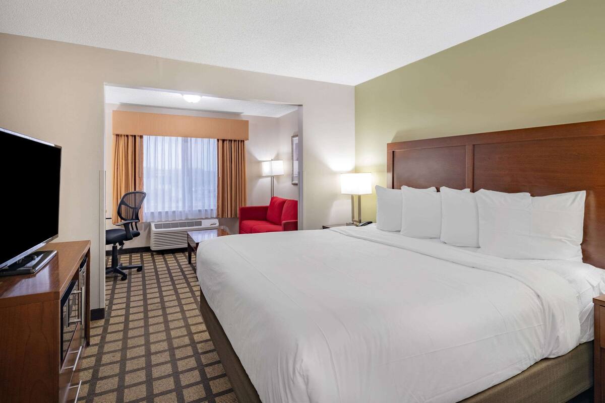 A hotel room with a large bed, a TV, a desk, and a chair.