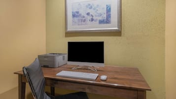 Un escritorio de madera con un monitor de computadora, teclado, ratón e impresora.