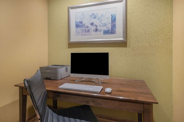 Un escritorio de madera con un monitor de computadora, teclado, ratón e impresora.