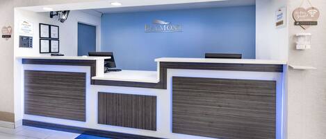 A reception desk at Baymont Inn & Suites with a blue wall, two counters, and a check-in area.