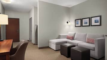 Una habitación de hotel moderna con un sofá modular, una mesita y una lámpara.